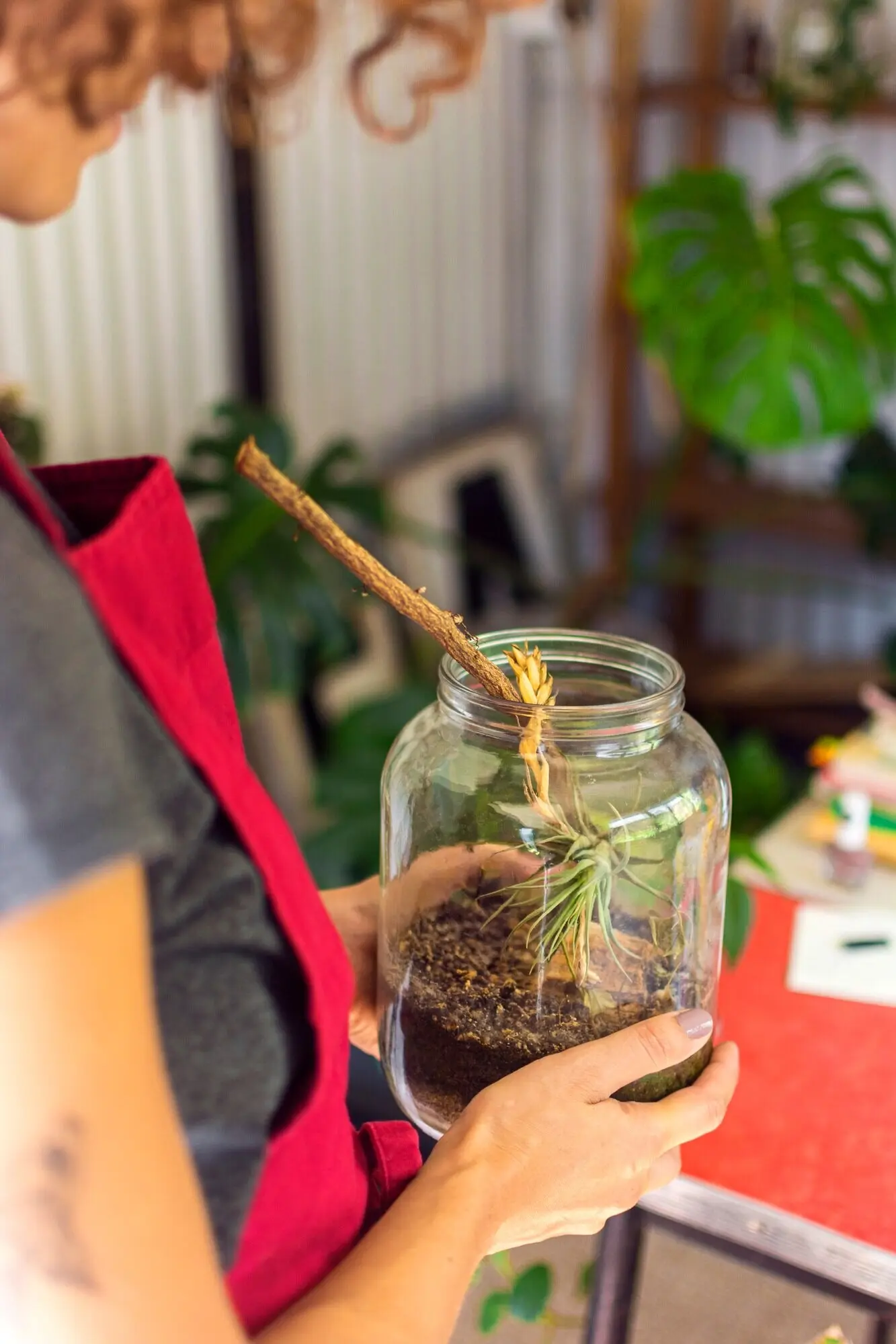 Side view of a woman caring for a plant in a jar.